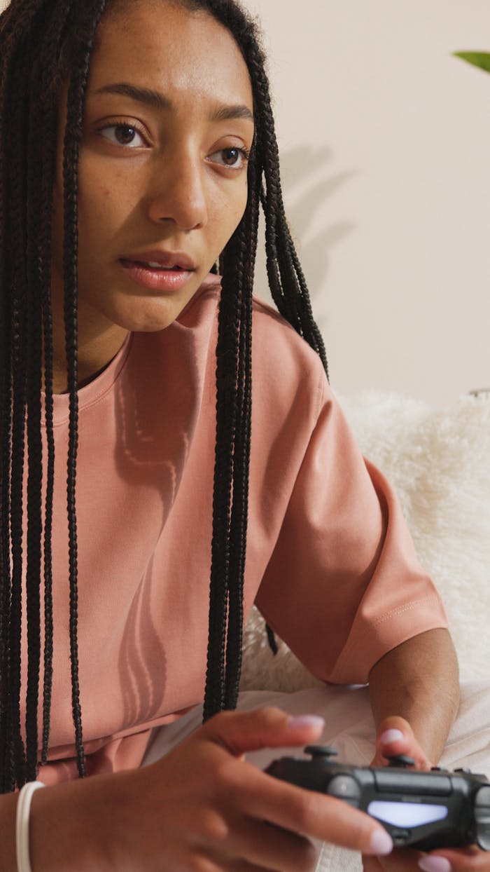 Focused woman with braided hair playing video game indoors.